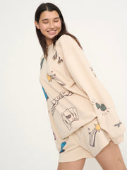 Woman wearing a beige sweater with colorful graphics on a white background