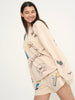 Woman wearing a beige sweater with colorful graphics on a white background