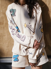 Person wearing a white sweatshirt and shorts with colorful graphics and text.