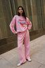 Person wearing a pink outfit with 'Graffiti' text, standing against a stone wall.