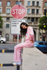 Person in pink outfit sitting on a street corner with a 'Stop' sign and 'Gratitude Starts Here' sign in the background.
